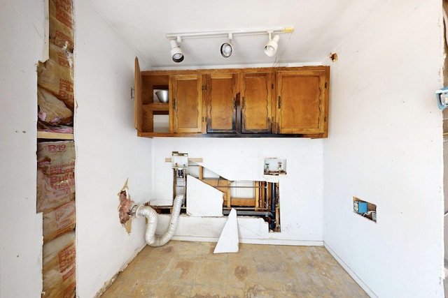 kitchen featuring brown cabinetry, rail lighting, and unfinished concrete floors