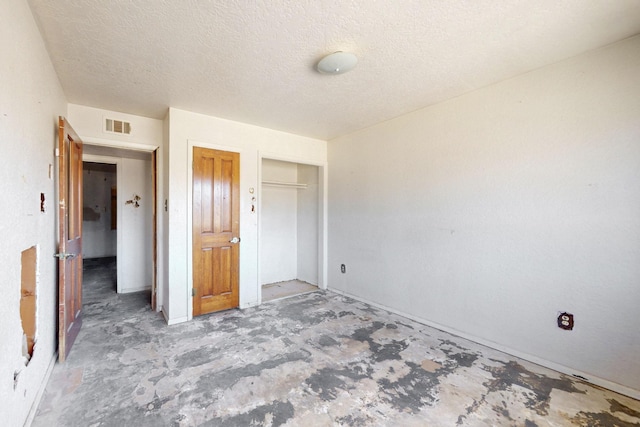 unfurnished bedroom with a textured ceiling, visible vents, and a closet