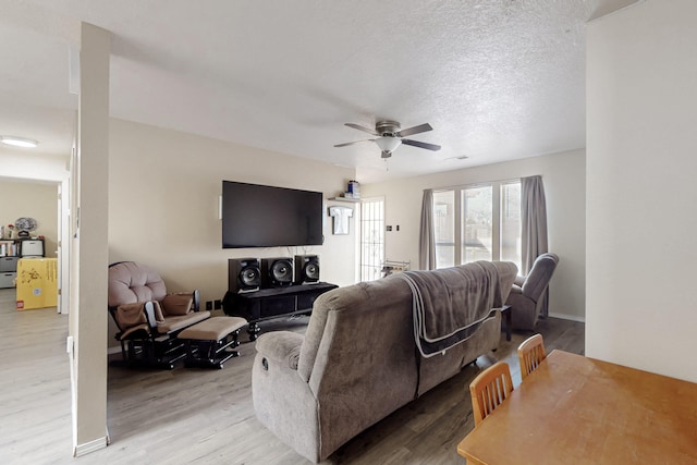 living room featuring a textured ceiling, ceiling fan, and light hardwood / wood-style floors