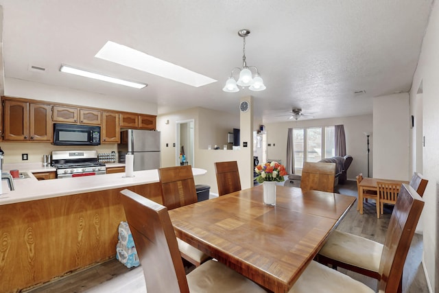 dining area featuring light hardwood / wood-style floors, ceiling fan, and a skylight