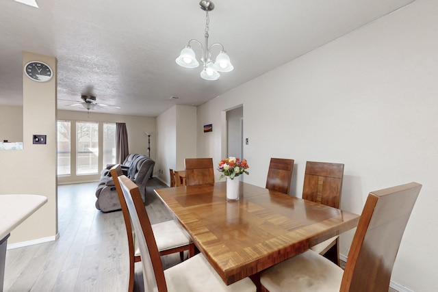 dining space featuring light wood-type flooring, a textured ceiling, and ceiling fan with notable chandelier