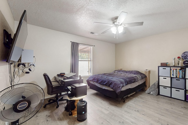 bedroom with light wood-type flooring, a textured ceiling, and ceiling fan