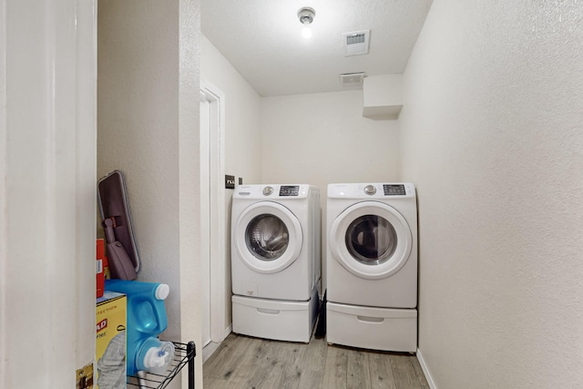 laundry room with independent washer and dryer and light wood-type flooring