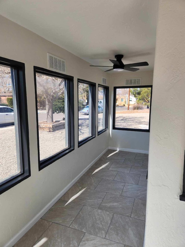 unfurnished sunroom featuring a wealth of natural light and ceiling fan