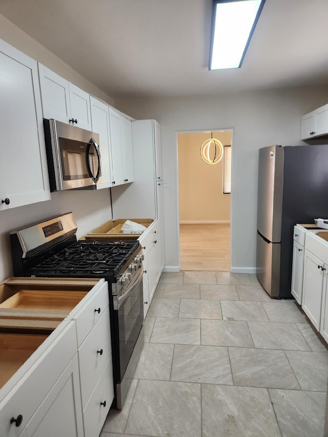 kitchen with white cabinets, hanging light fixtures, and appliances with stainless steel finishes