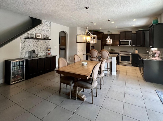 dining area with light tile patterned floors, beverage cooler, arched walkways, and recessed lighting