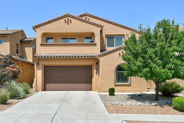 mediterranean / spanish-style house featuring a garage, concrete driveway, a tiled roof, and stucco siding