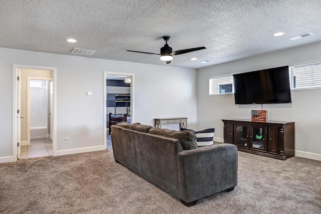 living area featuring baseboards, visible vents, ceiling fan, and light colored carpet