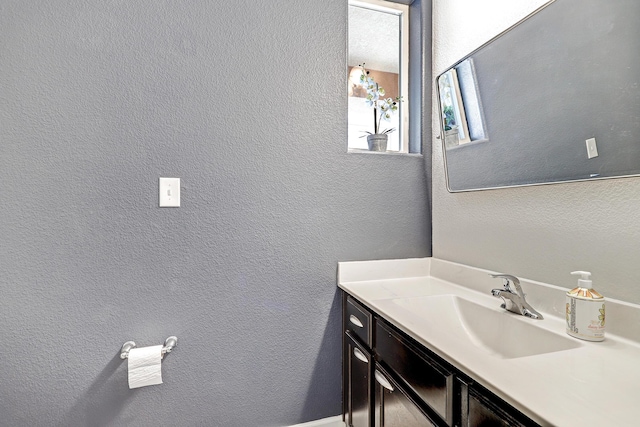 bathroom featuring a textured wall and vanity