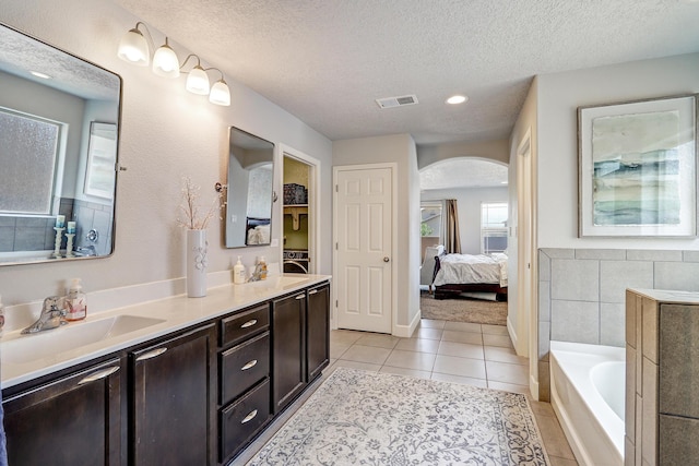 bathroom featuring ensuite bathroom, a textured ceiling, vanity, and visible vents