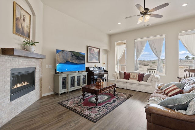 living room featuring a fireplace, ceiling fan, and dark wood-type flooring