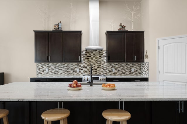 kitchen featuring a kitchen island with sink, a breakfast bar, and light stone counters