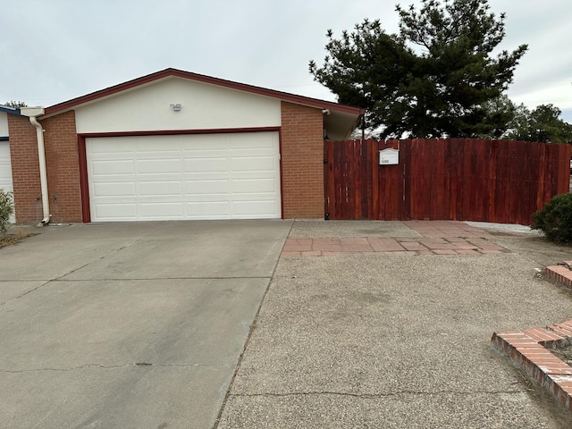 garage featuring concrete driveway and fence