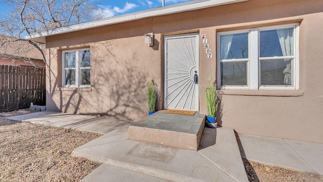 doorway to property with fence, a patio, and stucco siding