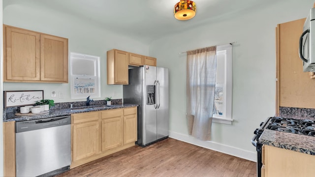 kitchen featuring light wood-style flooring, light brown cabinets, stainless steel appliances, and a sink