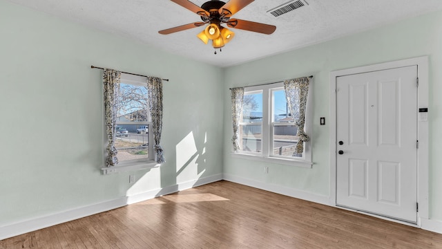 entrance foyer featuring visible vents, light wood-style flooring, baseboards, and a textured ceiling