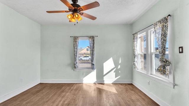 spare room with wood finished floors, a wealth of natural light, and baseboards