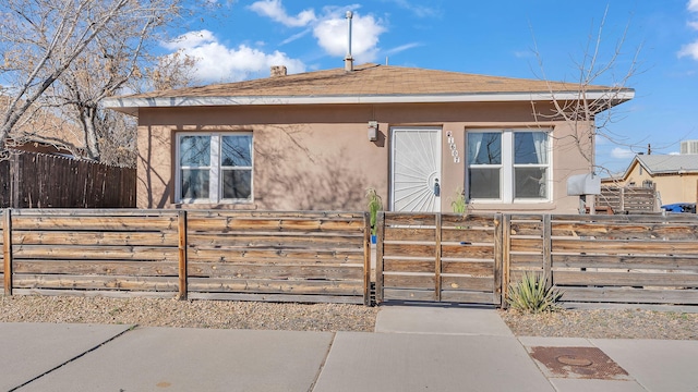 exterior space featuring a fenced front yard, a gate, and stucco siding