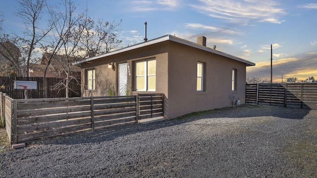 property exterior at dusk with fence and stucco siding