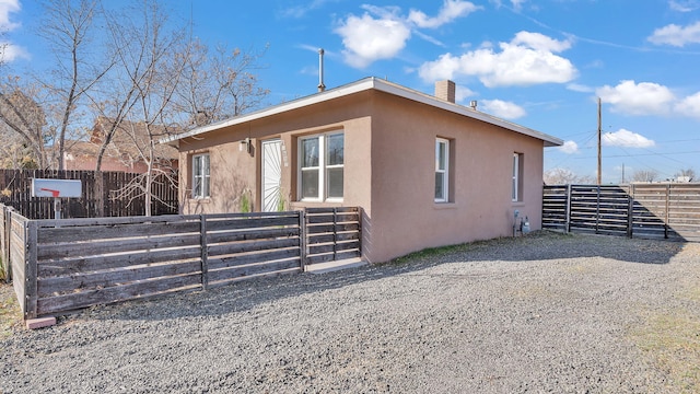 view of side of property with a chimney, fence, and stucco siding