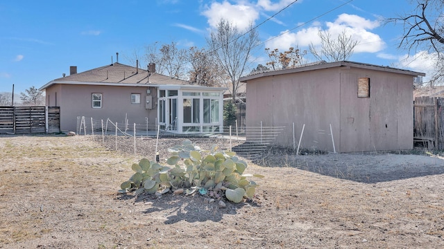 rear view of house with fence and a sunroom