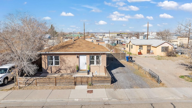 view of front of house with gravel driveway, a fenced front yard, a residential view, and stucco siding