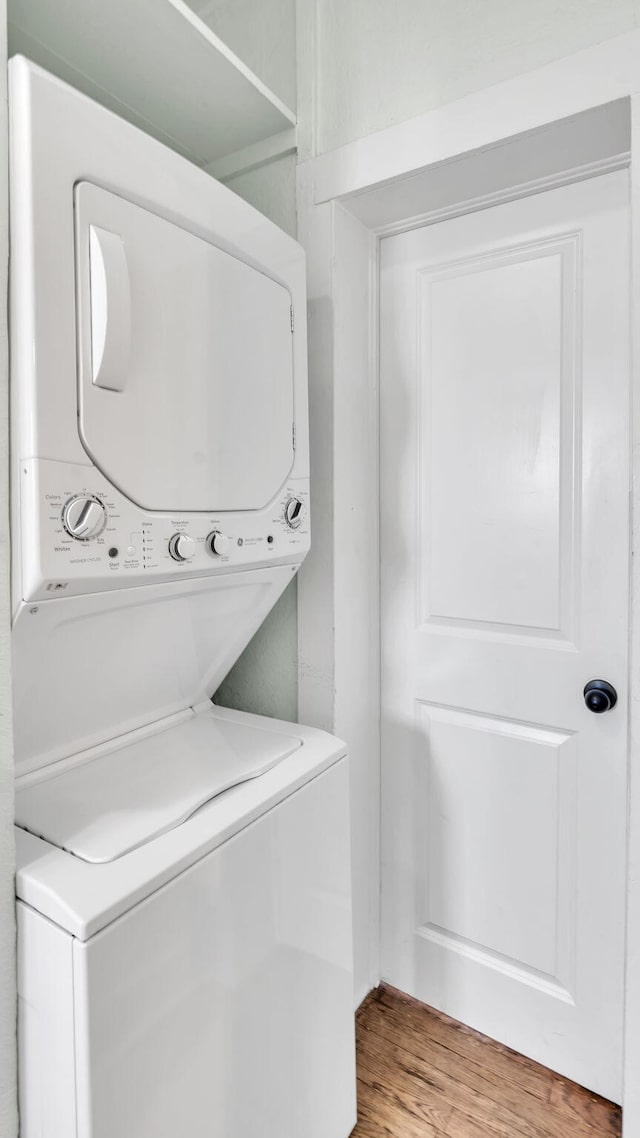 clothes washing area with stacked washer and clothes dryer, light wood-style flooring, and laundry area