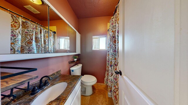 bathroom featuring visible vents, vanity, toilet, and a textured ceiling