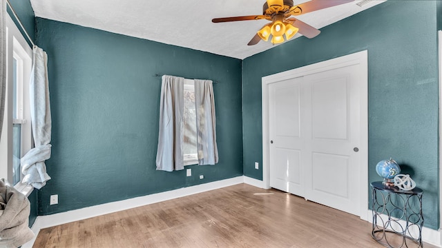 bedroom with ceiling fan, a closet, light wood-style flooring, and baseboards