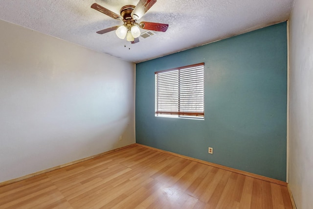 unfurnished room featuring a textured ceiling, wood finished floors, visible vents, and a ceiling fan