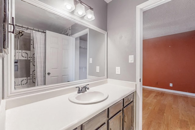 full bath with a shower with curtain, baseboards, wood finished floors, and vanity