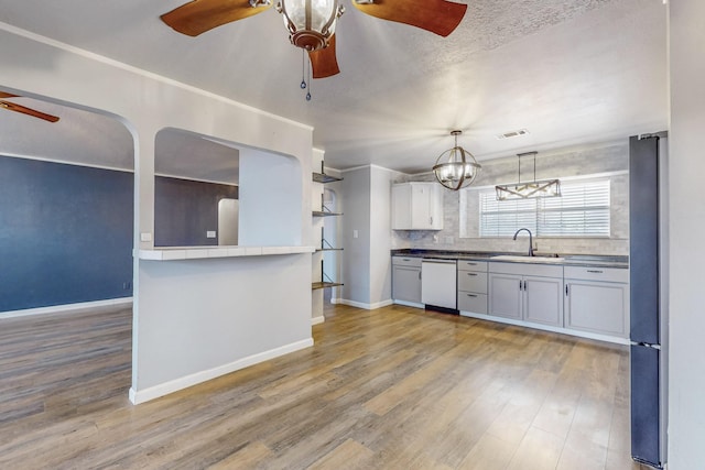 kitchen with dishwasher, wood finished floors, freestanding refrigerator, white cabinetry, and a sink