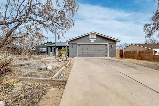 ranch-style house with a garage, driveway, fence, and stucco siding