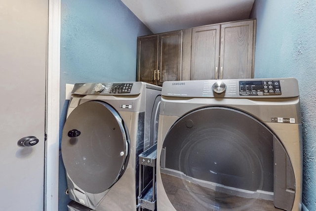 washroom featuring washer and dryer, cabinet space, and a textured wall