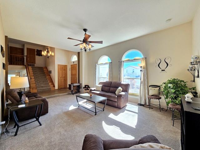 living room with ceiling fan with notable chandelier, light colored carpet, and stairs