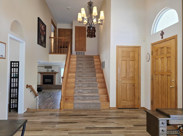 entrance foyer featuring a high ceiling, visible vents, a fireplace with raised hearth, and wood finished floors