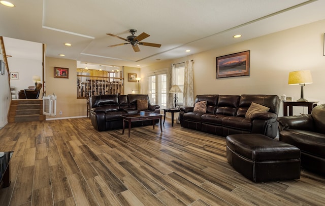 living area with recessed lighting, stairway, a tray ceiling, and wood finished floors