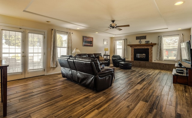 living room with a healthy amount of sunlight, a fireplace, and dark wood finished floors