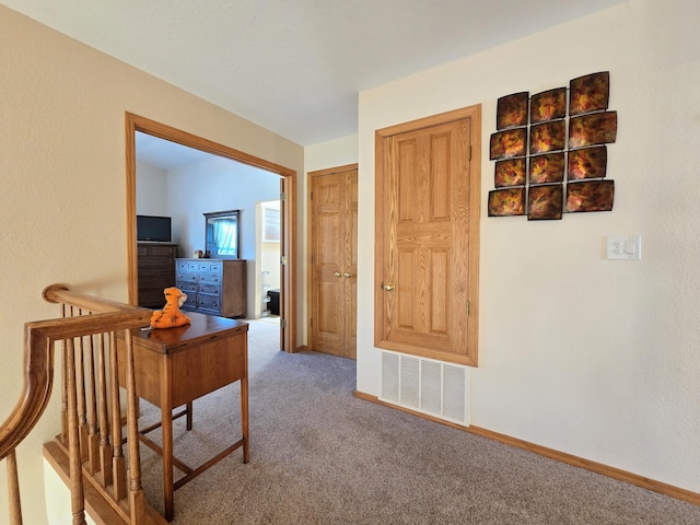 hall featuring carpet floors, visible vents, and baseboards