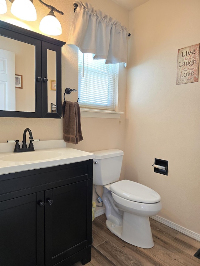 bathroom with baseboards, vanity, toilet, and wood finished floors