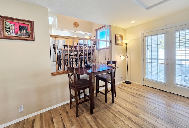 dining room featuring plenty of natural light, light wood-style flooring, baseboards, and french doors