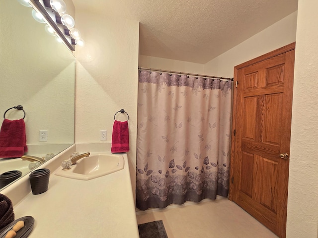 full bath featuring a textured wall, a textured ceiling, and vanity