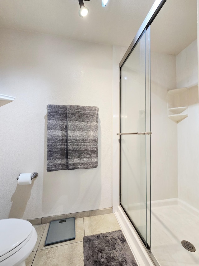 full bath with toilet, a stall shower, baseboards, and tile patterned floors