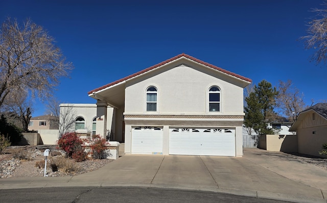 traditional home with a garage, a tile roof, driveway, and stucco siding