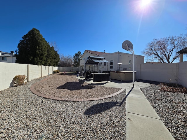 view of yard with a patio area, a fenced backyard, and a hot tub