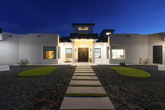 exterior entry at twilight featuring stucco siding