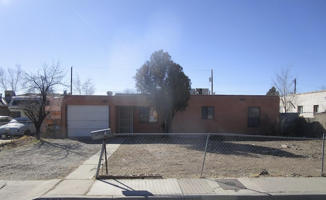 adobe home with fence, stucco siding, and a garage