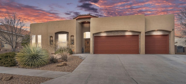 southwest-style home featuring concrete driveway, an attached garage, and stucco siding