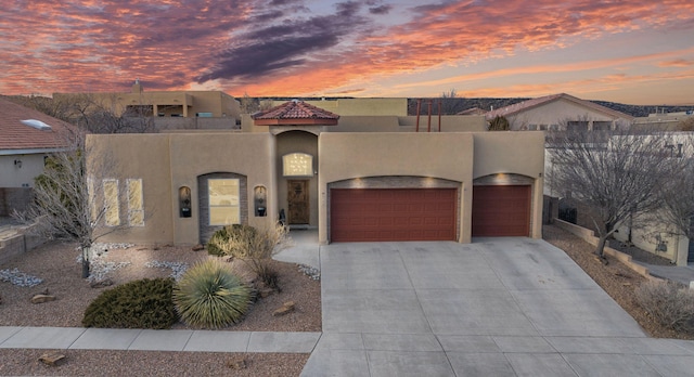 view of front of home featuring stucco siding, an attached garage, and driveway