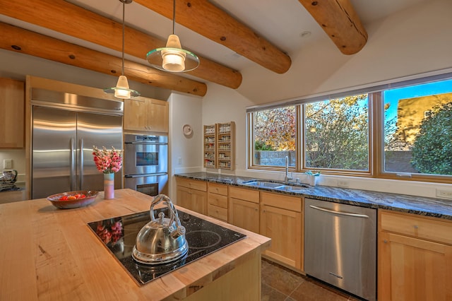 kitchen featuring butcher block countertops, a sink, appliances with stainless steel finishes, light brown cabinetry, and decorative light fixtures